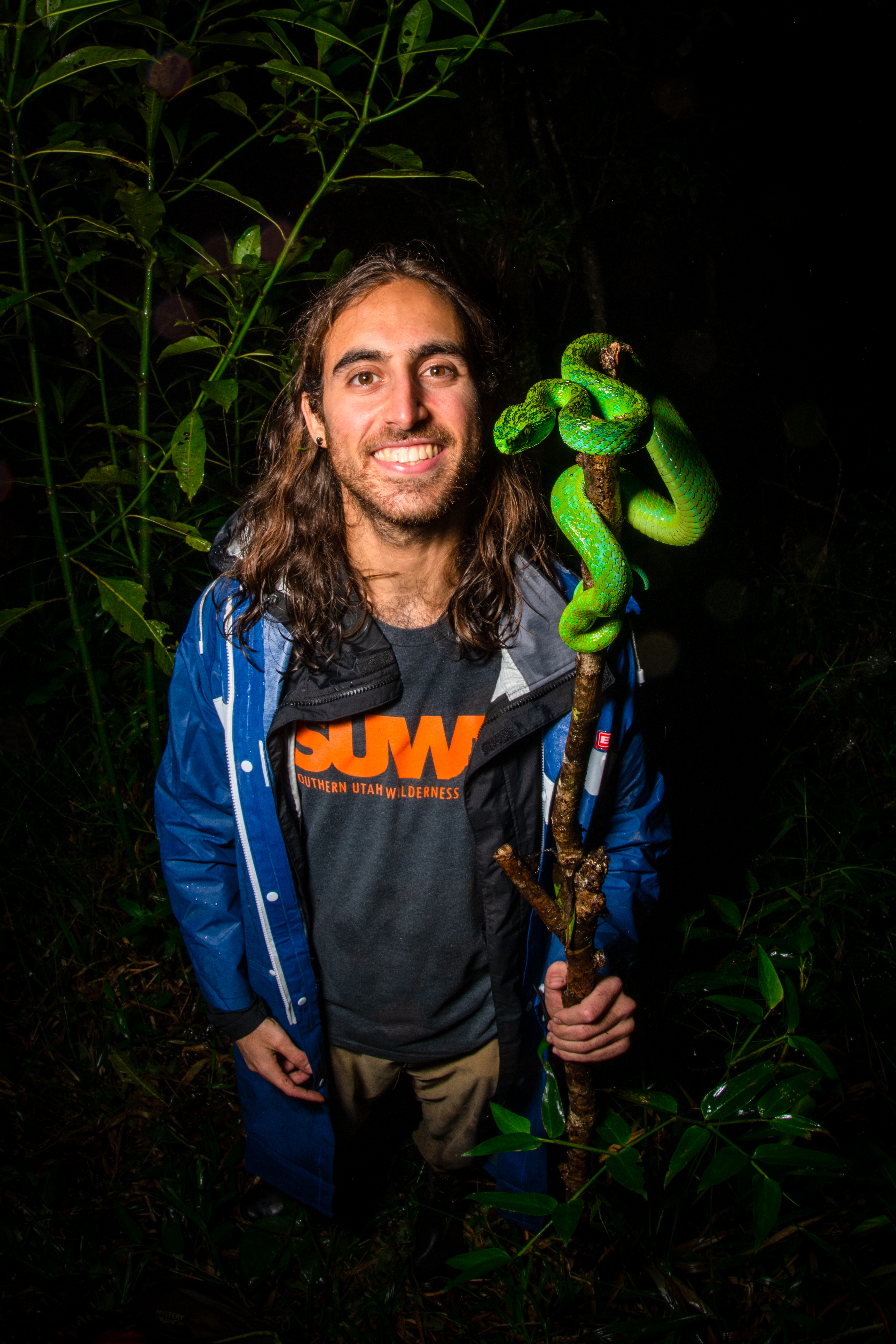 Picture of Taz holding a stick with a palm pit viper wrapped around it